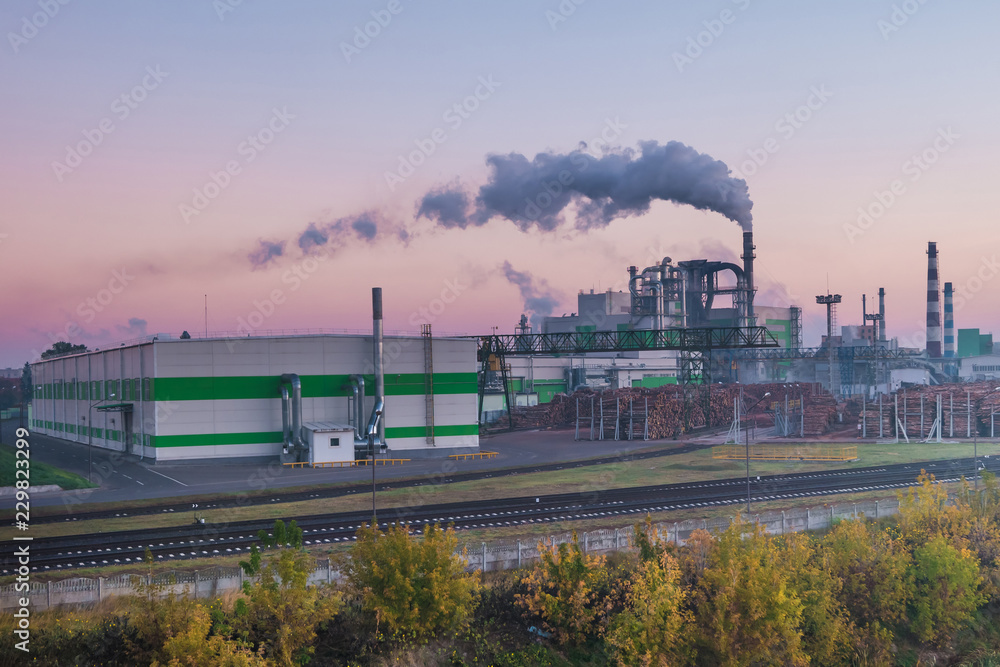 pipes of woodworking enterprise plant sawmill in the morning dawn. Air pollution concept. Industrial landscape environmental pollution waste of thermal power plant