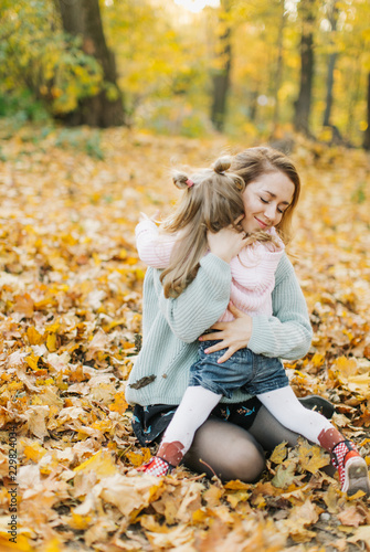 young mother with daughter are walking in the park in the golden autumn