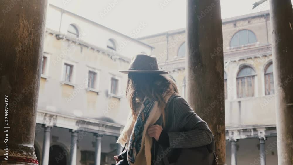 Beautiful female professional photographer with camera taking photos at ancient building pillars in old town of Venice.