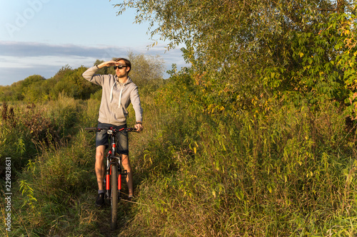 Young man cycling outdoors in summer, autumn in nature, copy space