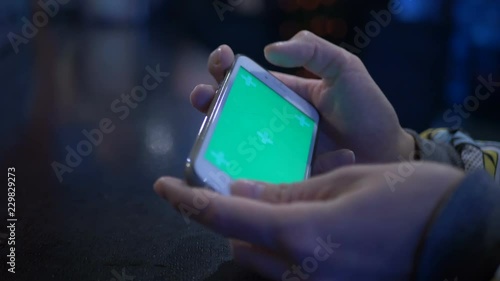 Beautiful girl holding a smartphone in the hands of a green screen green screen, hand of man holding mobile smart phone with chroma key green screen on white background, new technology concept.