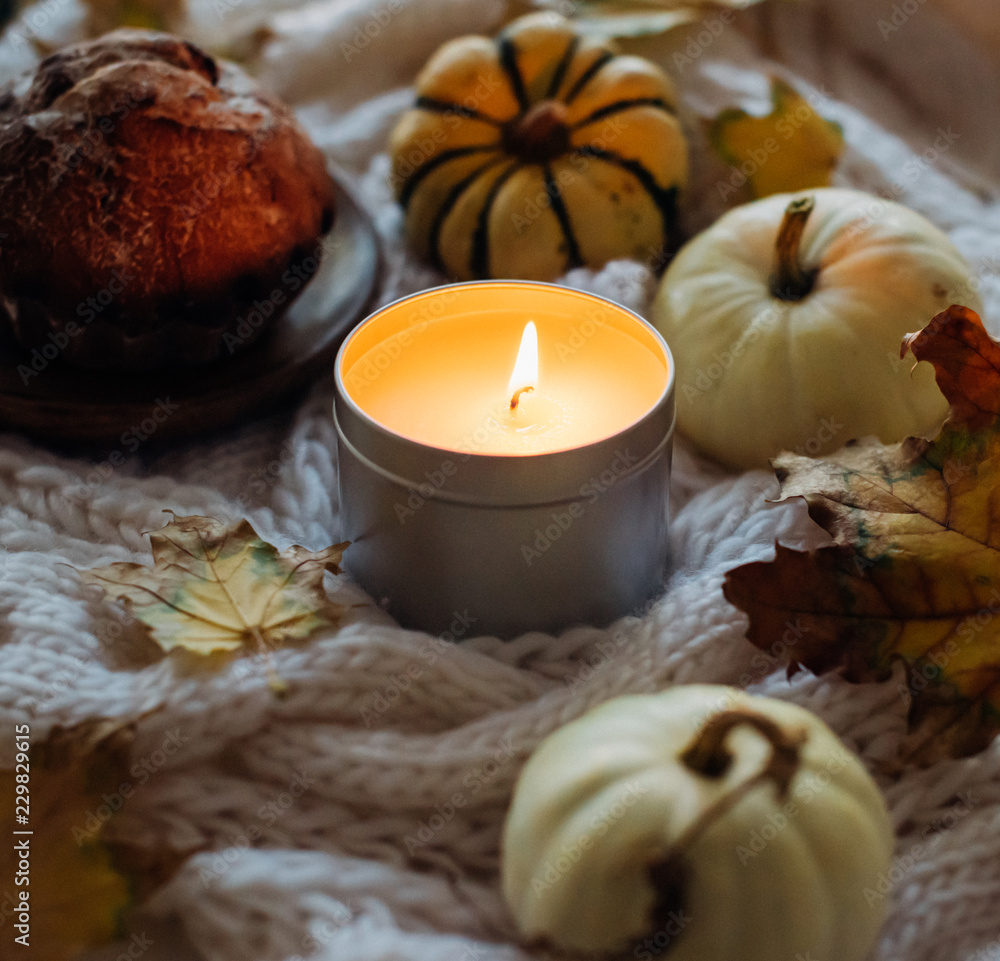 Burning candle in jar, autumn leaves and small decorative pumpki Burning candle in jar, autumn leaves and small decorative pumpki