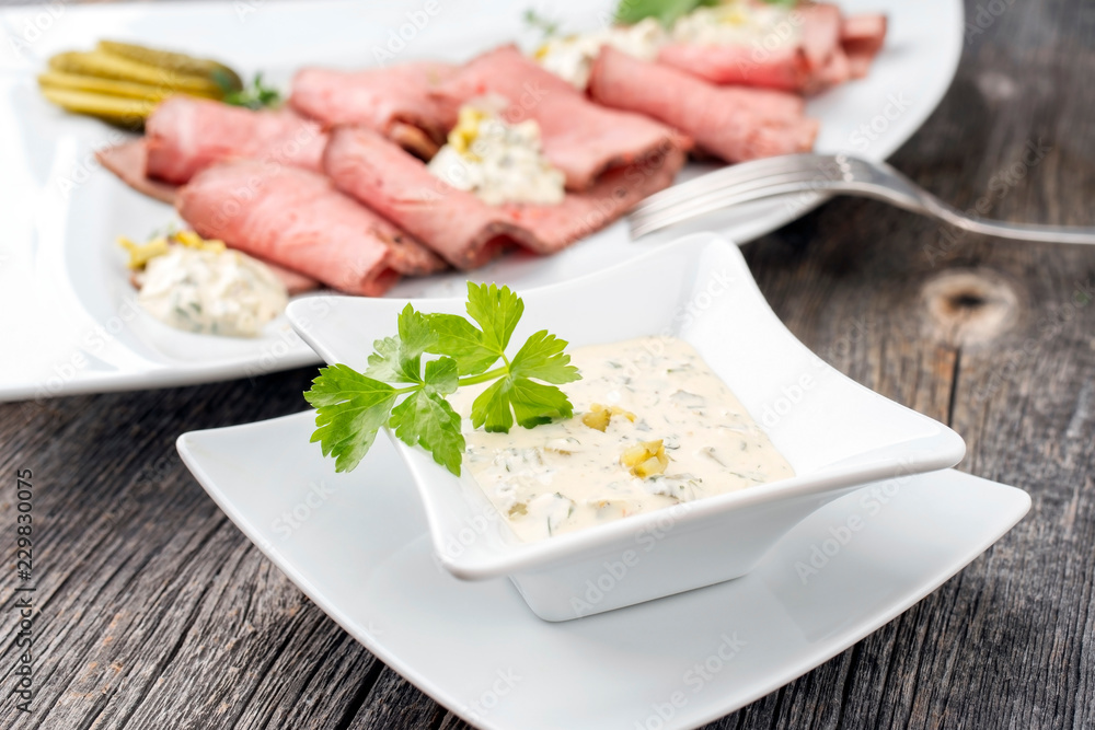 Traditional lunch meat with sliced cold cuts roast beef and remoulade as closeup on a white plate Traditional lunch meat with sliced cold cuts roast beef and remoulade as closeup on a white plate