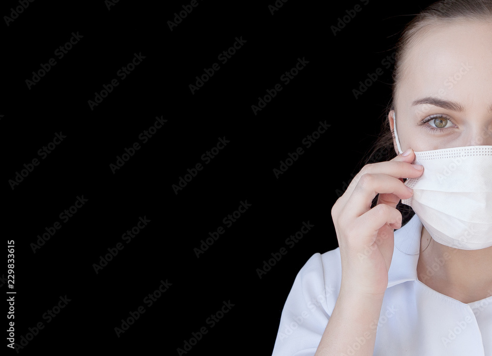 A front view of a young intellectual doctor in a medical mask on a black background with text space