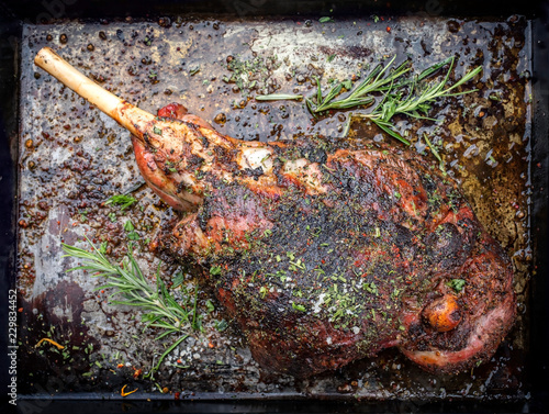 Traditional barbecue leg of lamb with spice and herb as top view on a metal sheet