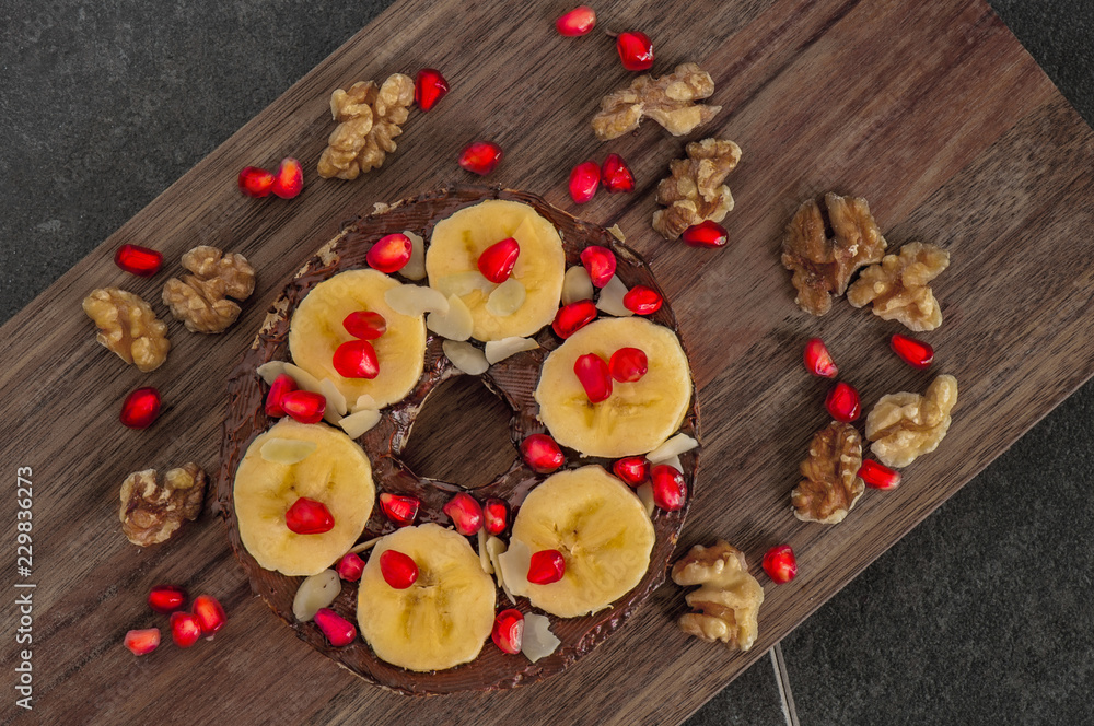 Bagel mit Granatapfelkernen und Bananenscheiben Bagel mit Granatapfelkernen und Bananenscheiben