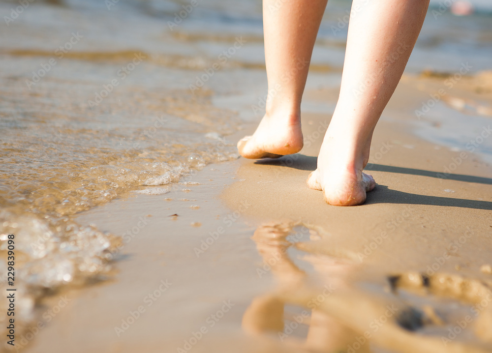 Woman walking on sand beach leaving footprint in the sand. Beach travel Woman walking on sand beach leaving footprint in the sand. Beach travel