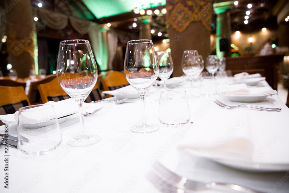 Beautifully decorated table with empty white plates, glasses and cutlery  on luxurious tablecloths