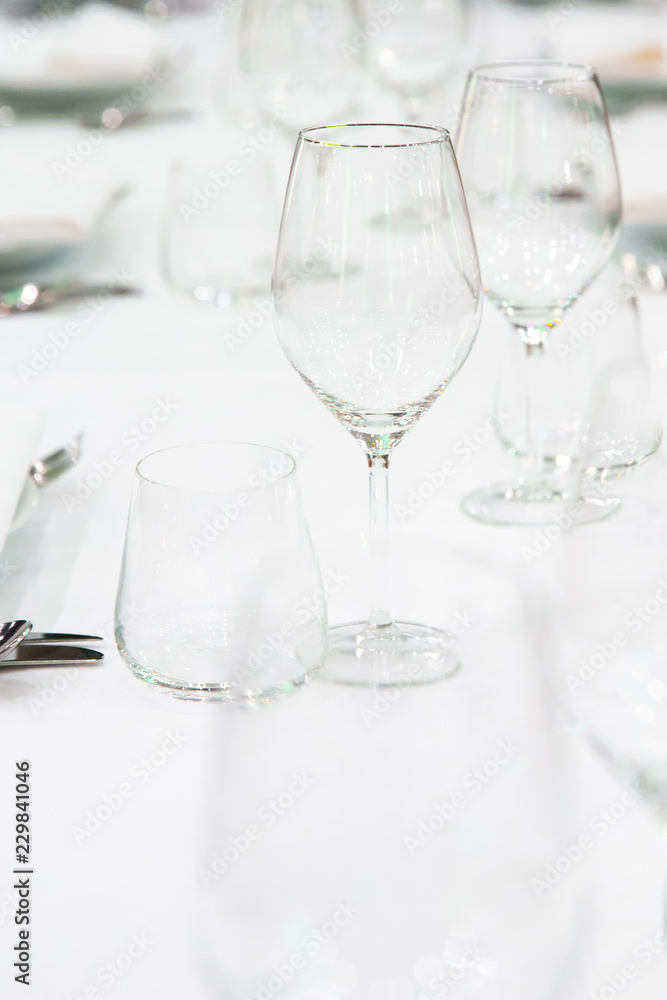 Beautifully decorated table with empty white plates, glasses and cutlery on luxurious tablecloths Beautifully decorated table with empty white plates, glasses and cutlery on luxurious tablecloths