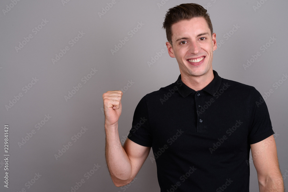 Young handsome man looking excited against gray background Young handsome man looking excited against gray background