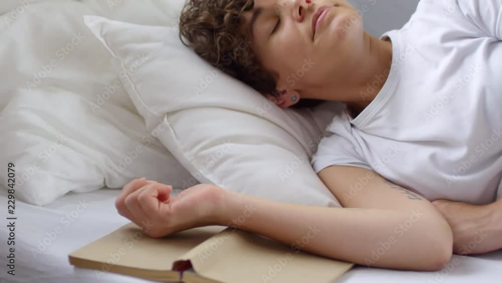 Tracking shot of happy woman with short curly hair sleeping in cozy bed, then waking up and stretching Tracking shot of happy woman with short curly hair sleeping in cozy bed, then waking up and stretching