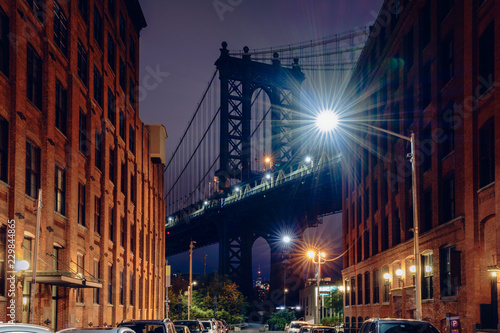 Brooklyn bridge seen from a narrow alley enclosed by two brick buildings at dusk, NYC USA