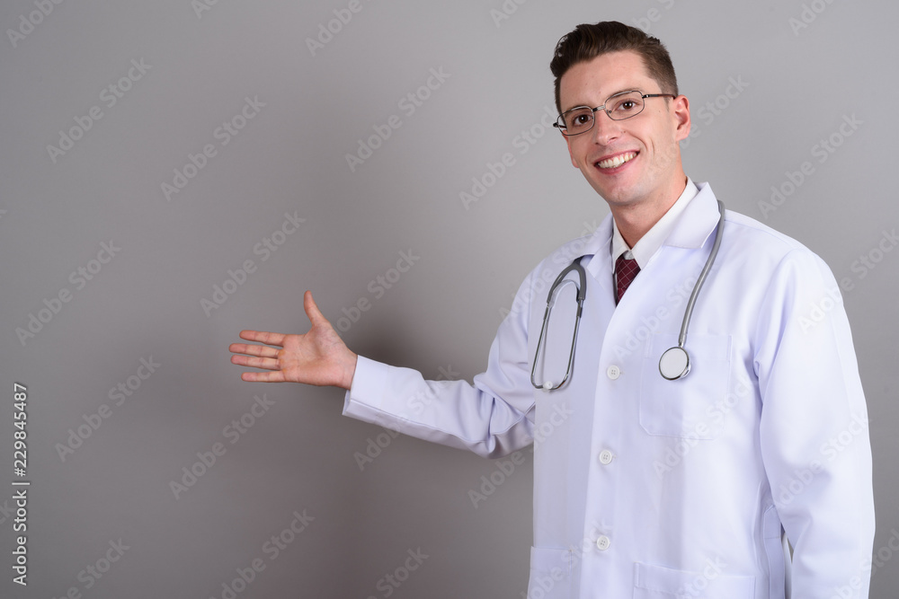 Young handsome man doctor smiling and showing copy space Young handsome man doctor smiling and showing copy space