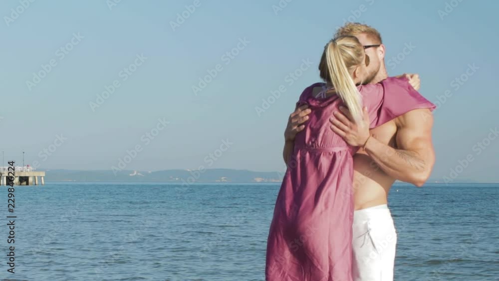 Young couple share a kiss in the sunshine on the beach Young couple share a kiss in the sunshine on the beach