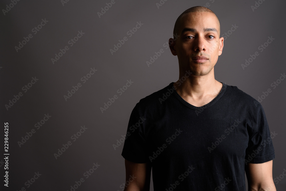 Fototapeta premium Handsome bald man wearing black shirt against gray background