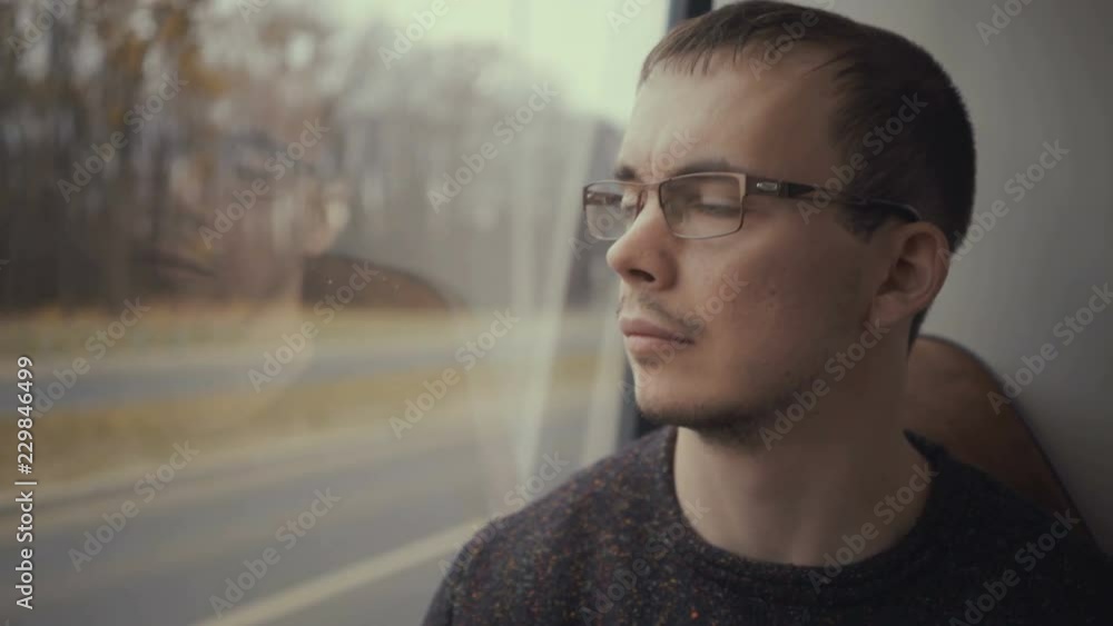 young man looking out the window during bus ride young man looking out the window during bus ride