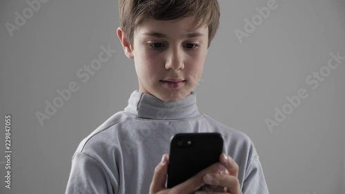 Portrait of Young Child Boy using Smartphone on white background. Boy plaing games on smartphone. photo