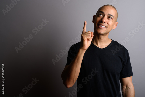 Handsome bald man thinking and pointing finger up photo