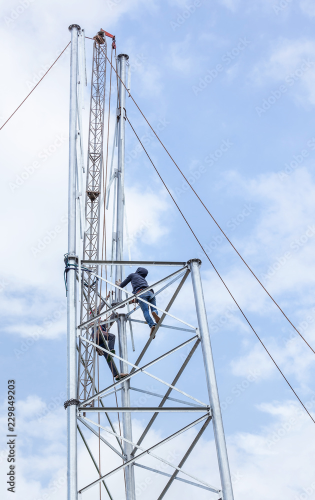 Electricians working in the height for installation antenna communication metal high tower 
