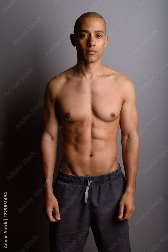 Handsome bald man shirtless against gray background