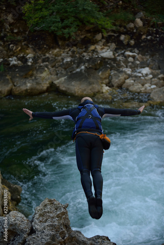 Man jumping in wild river photo
