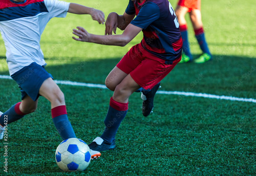 football teams - boys in red, blue, white sportswear play soccer on the green field. boys dribbling. dribbling skills. Team game, training, active lifestyle, hobby, sport for kids concept
