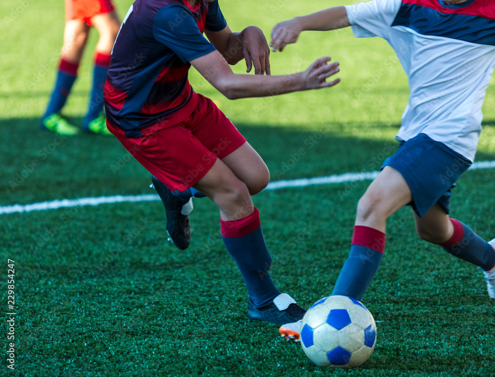 football teams - boys in red, blue, white sportswear play soccer on the green field. boys dribbling. dribbling skills. Team game, training, active lifestyle, hobby, sport for kids concept