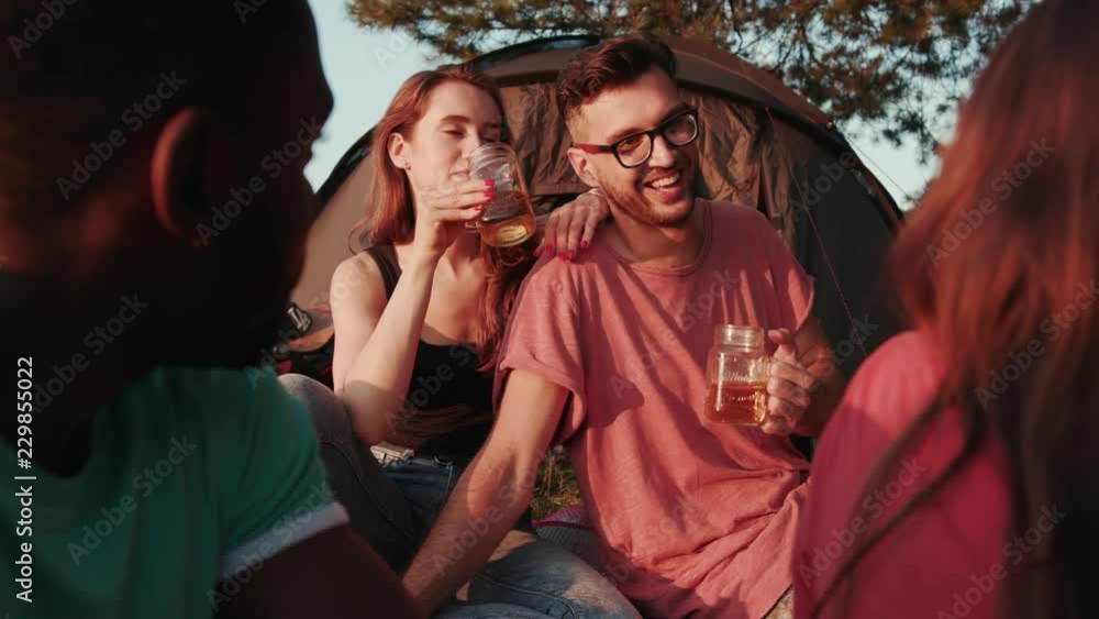 Joyous young people by the tourist tent chatting, joking with their friends, hanging out and laughing happily. Coziness, double date, hobby. Active lifestyle, true friendship