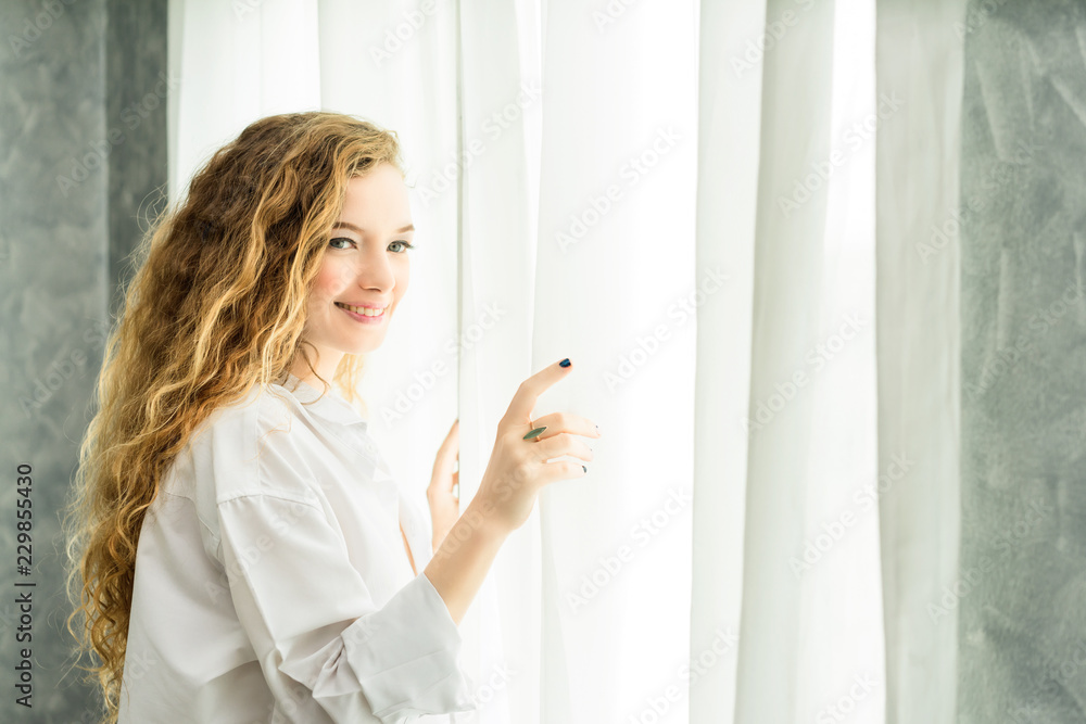 Young women are relaxing after waking up in the morning.Young woman stand up looking at the window relaxing in her bedroom Young women are relaxing after waking up in the morning.Young woman stand up looking at the window relaxing in her bedroom