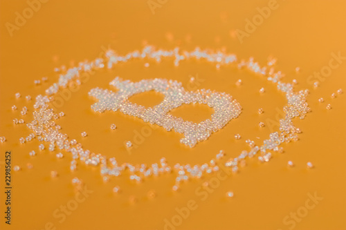 Symbol of bitcoin from beads on a orange background