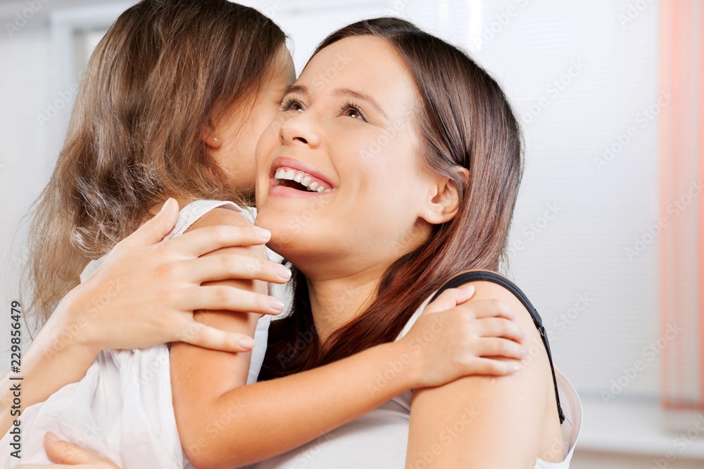 Mother and daughter hugging in bright bedroom Mother and daughter hugging in bright bedroom