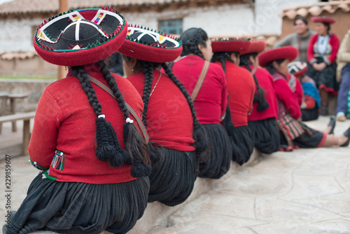 Quadro su tela Quechua women sitting in a line with their traditional dress and braided hairstyle in Peru