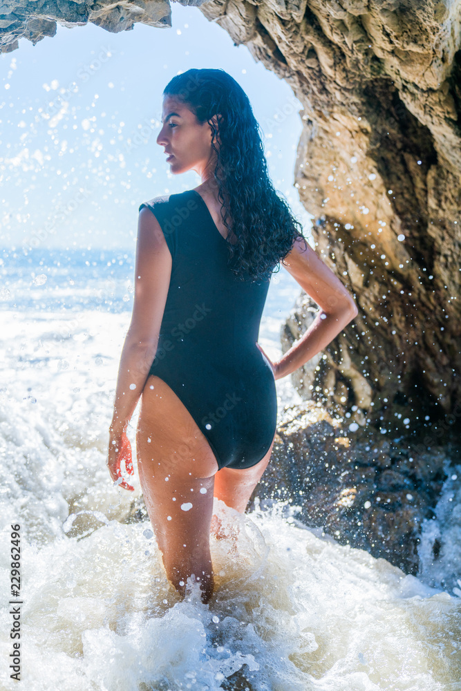 Portrait of latino woman with curly hair, black swimsuit at beach Portrait of latino woman with curly hair, black swimsuit at beach
