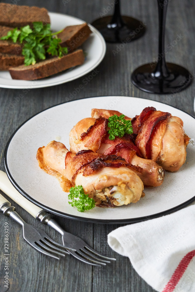 Baked chicken legs with bacon on a plate Baked chicken legs with bacon on a plate