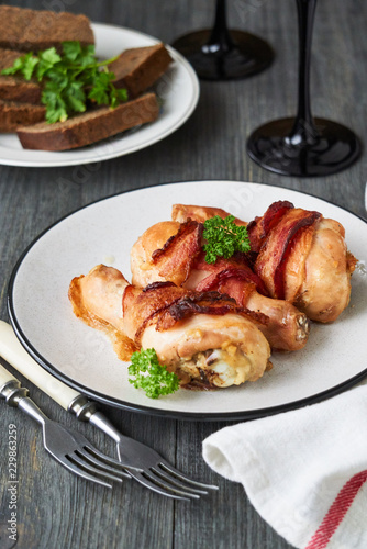Baked chicken legs with bacon on a plate