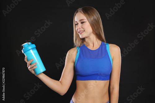 Portrait of woman with bottle of protein shake on black background