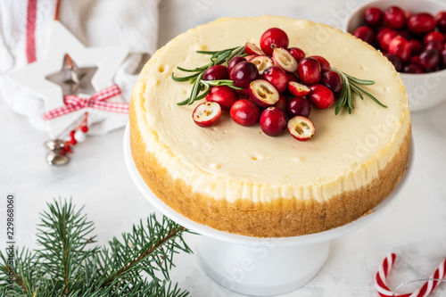 Cheescake with fresh cranberry and rosemary. Christmas cake with decoration on white background.