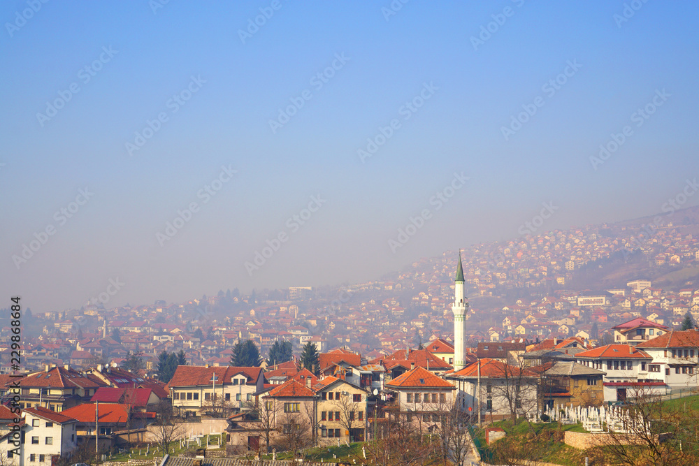 Beautiful landscape of old town Sarajevo,Bosnia and Herzegovina with roofs, houses, mosque and cemetery  cover with smog and blue sky in winter,scenic high viewpoint.