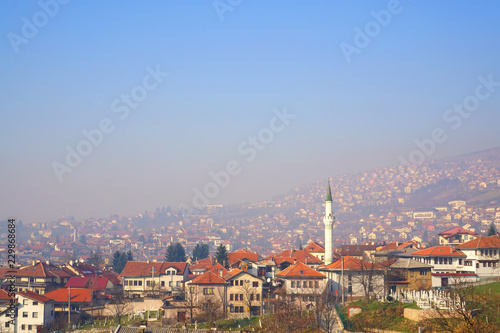 Beautiful landscape of old town Sarajevo,Bosnia and Herzegovina with roofs, houses, mosque and cemetery cover with smog and blue sky in winter,scenic high viewpoint.