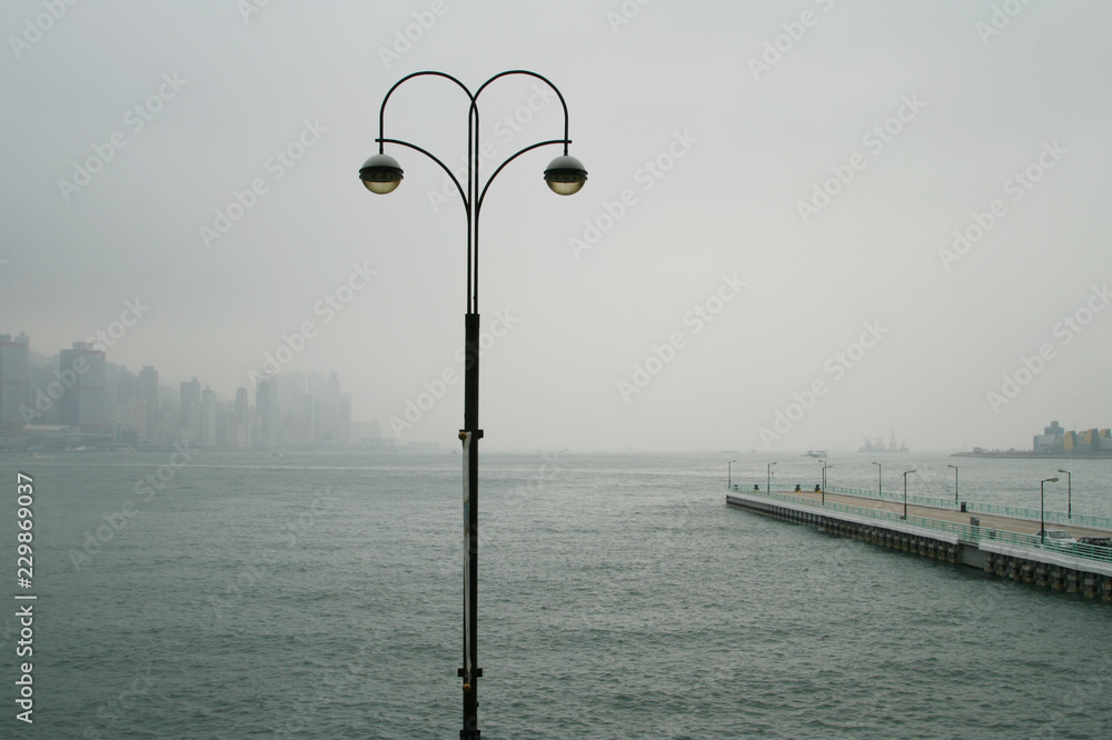 Street light post at Victoria Harbor with Hong Kong Island in the distance.