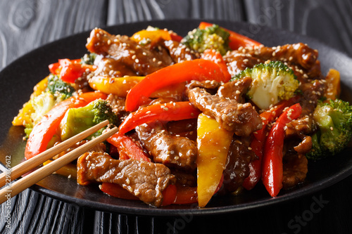Canvas Print Stir-fried teriyaki beef with red and yellow bell pepper, broccoli and sesame seeds close-up on the table