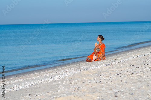 Woman relaxes and meditates on a deserted beach