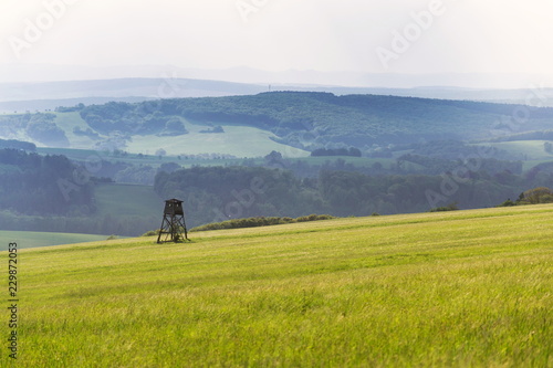 Deer stand, wooden hunters high seat hide on field, summer day, cloudy dramatic sky, Bojkovice, Uherske Hradiste district, Zlin region, White Carpathians, Czech Republic