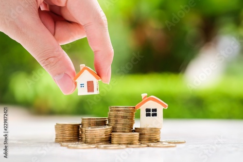 Hand choosing house model on coins stack. Planning to buy suitable home. Real estate, Refinance, Property investment and asset management concept. Decision to choose the best property with your right.