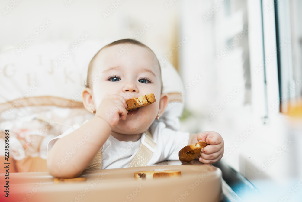 Baby girl eating cracker with raisins in a chair Baby girl eating cracker with raisins in a chair