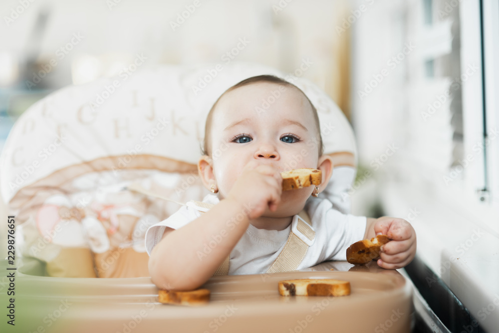 Baby girl eating cracker with raisins in a chair Baby girl eating cracker with raisins in a chair