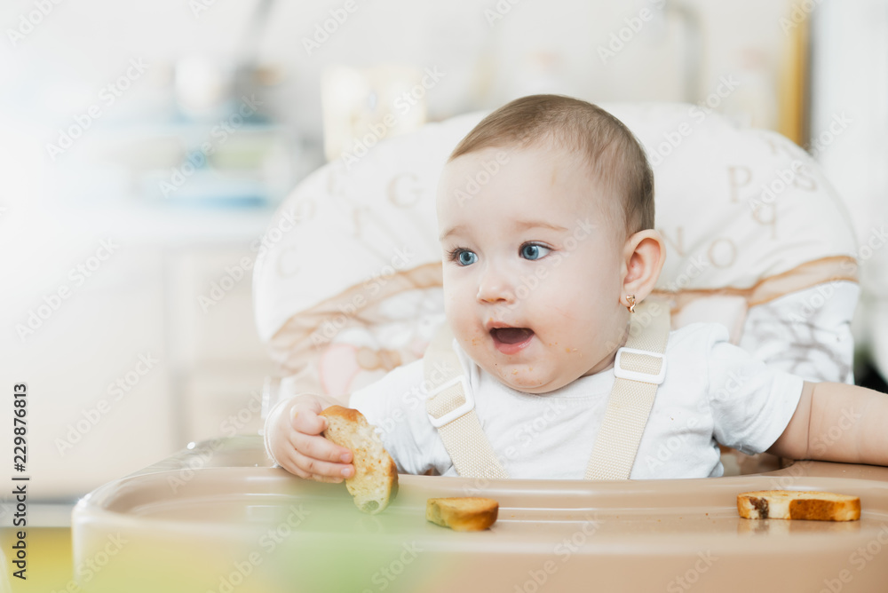 Baby girl eating cracker with raisins in a chair Baby girl eating cracker with raisins in a chair