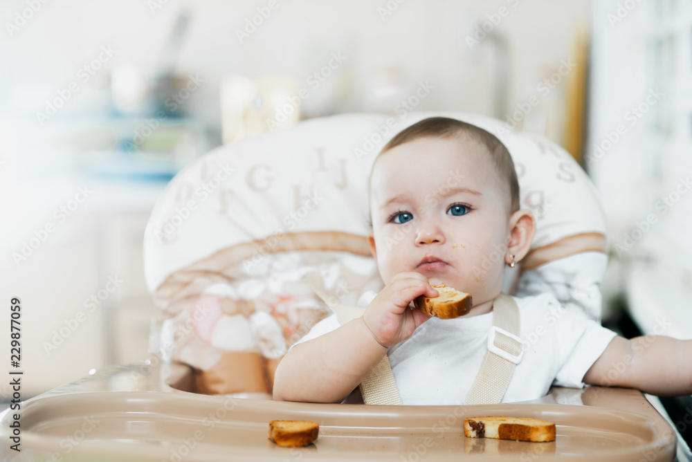 Baby girl eating cracker with raisins in a chair Baby girl eating cracker with raisins in a chair