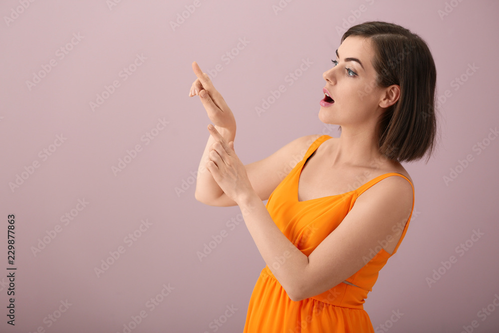 Portrait of beautiful young woman pointing at something on color background Portrait of beautiful young woman pointing at something on color background