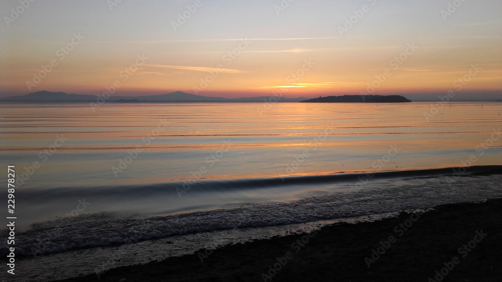 Umbria, italy, a glimpse of Trasimeno lake at sunset with Isola Maggiore on background Umbria, italy, a glimpse of Trasimeno lake at sunset with Isola Maggiore on background